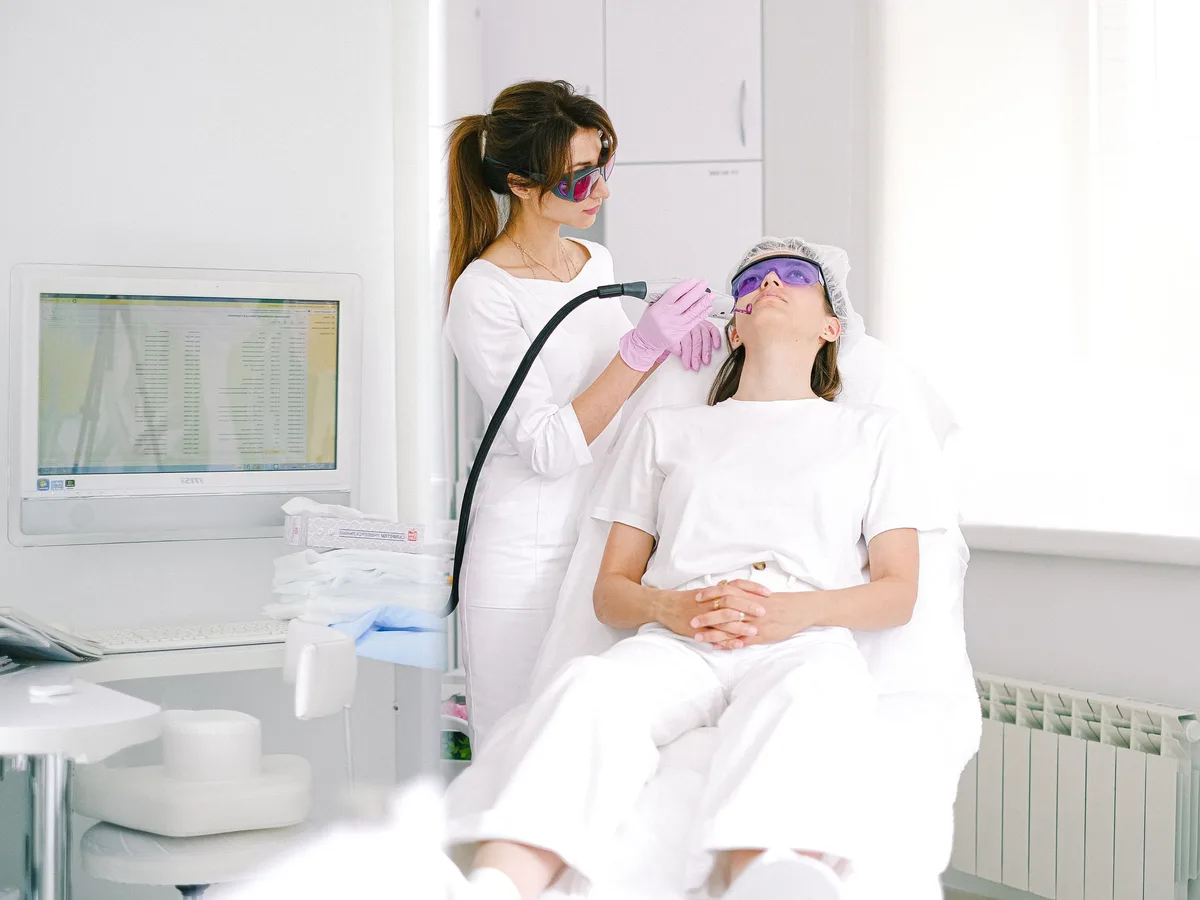 Laser handpiece being used on a patient's face, both wearing protective goggles
